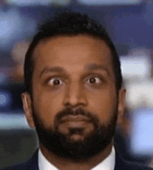 a man with a beard wearing a suit and tie is making a funny face