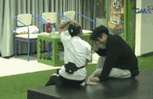 two men sit on a bench in front of a vending machine that says freeze