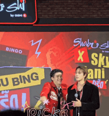 two men standing in front of a screen that says bingo on it