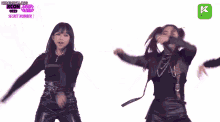 two women are dancing on a stage with their arms in the air .