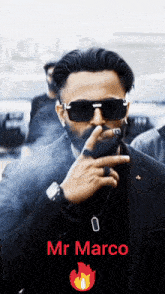 a man in a suit and sunglasses smoking a cigar with the name mr marco on the bottom right
