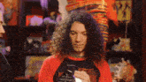 a man with long curly hair wearing a red shirt that says ' warru ' on it