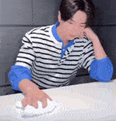 a man in a striped shirt is cleaning a white table