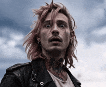a man with long hair and a tattoo on his neck is wearing a black jacket