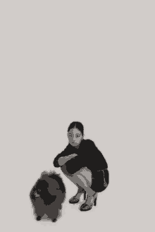 a woman is squatting next to a small black dog
