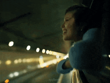 a woman is smiling while looking out of a window at night .