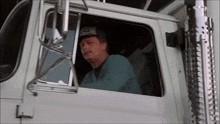 a man wearing a hat that says jc on it looks out the window of a truck