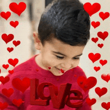 a young boy in a red sweater is surrounded by red hearts and a red love sign .