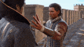 two men are standing next to each other and one of them is reaching out his hand towards the other man