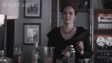 a woman in a black dress is standing in front of a bar with a bottle of vodka in the background