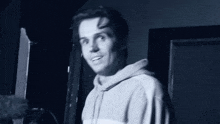 a man in a hoodie is standing in front of a door in a dark room .