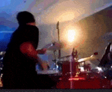 a blurred image of a person playing drums in a room