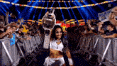 a woman is holding a championship belt in front of a crowd of people .