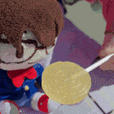 a person is holding a lollipop in front of a stuffed toy