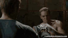 a man without a shirt is being punched by another man with the website shadowhunterstv.com visible in the corner