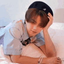 a young man is laying on a bed wearing a hat and a tie .