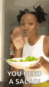 a woman is holding a bowl of salad and eating it with a fork .