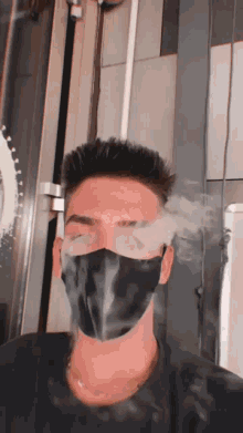 a man wearing a black face mask smoking a cigarette