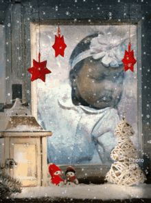 a picture of a baby in a window with snow falling in the background