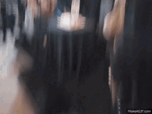a blurry picture of people standing around a table .