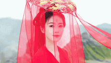 a woman wearing a red veil and a hat