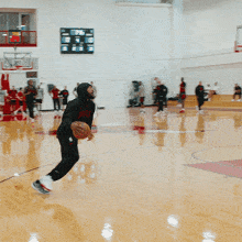 a man in a black jacket is dribbling a basketball on a basketball court with a spalding sign in the background