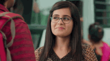 a woman wearing glasses is smiling while standing next to a man