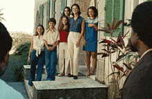 a group of women are posing for a picture on the steps of a house