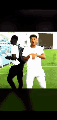 a man with a backpack stands next to another man on a field