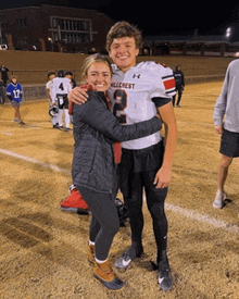 a football player with the number 2 on his jersey hugging a woman