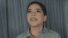 a woman wearing a green shirt and earrings looks up at something