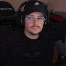 a man wearing headphones and glasses is sitting in front of a microphone and making a fist .
