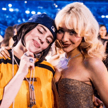 two women are posing for a picture and one is wearing a yellow shirt that says aee