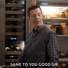 a man in a plaid shirt is standing in front of a refrigerator and saying same to you good sir .