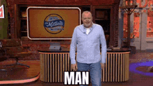 a man in a blue shirt is standing in front of a desk with the word man on it .