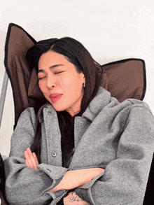 a woman with her eyes closed is wearing a grey coat