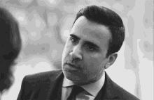 a man in a suit and tie is looking at the camera .