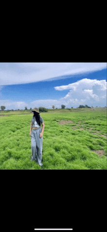 a woman in a straw hat is standing in a grassy field .