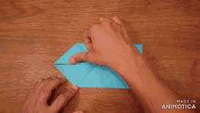 a person folding a piece of blue paper with the words made in animotica visible