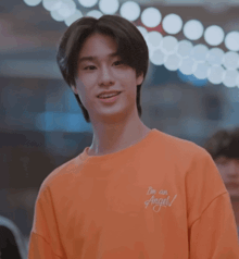 a young man wearing an orange shirt that says i 'm an angel on it
