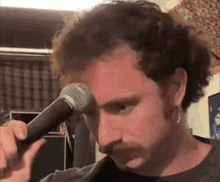 a man with a mustache is holding a microphone to his face
