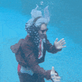 a man in a suit and scarf is swimming under water