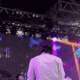 a man in a white shirt is standing in front of a stage with purple lights