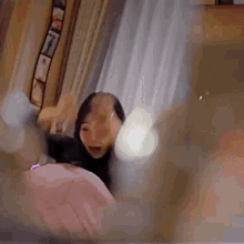a woman is sitting on a bed in a room with a blurred image of her face .