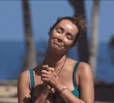 a woman in a blue bikini with a bracelet on her wrist