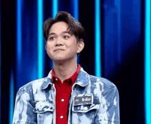 a young man wearing a denim jacket with a name tag that says into