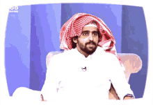 a man wearing a head scarf is sitting in front of a screen that says channels on it
