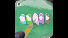 a person is painting a row of nails with a brush on a green plate .