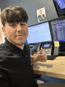 a young man is giving a thumbs up in front of a computer