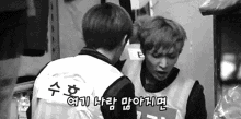 a black and white photo of two men standing next to each other and talking .